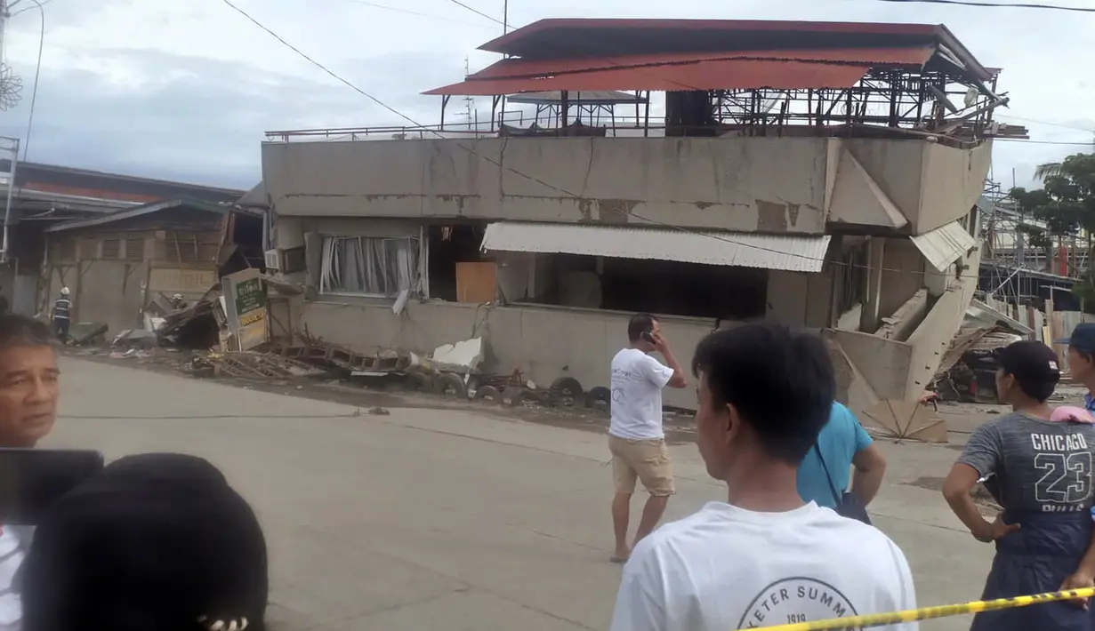 Penduduk melihat bangunan yang runtuh setelah gempa melanda Padada, provinsi Davao del Sur, Filipina selatan (15/12/2019). Gempa tersebut menyebabkan bangunan tiga lantai runtuh dan membuat warga panik bergegas keluar dari pusat perbelanjaan, rumah dan bangunan lain. (AP Photo/John Angelo Jomao-as)