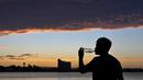 Seorang pria meminum air di bawah sinar matahari di sebuah pantai di Puerto Madryn, provinsi Chubut, Argentina pada tanggal 26 Januari 2024. (MAXI JONAS/AFP)