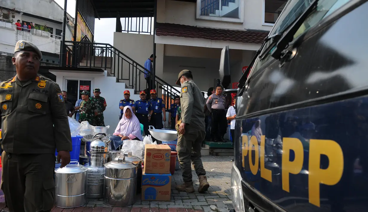 Satpol PP mengeluarkan barang dagangan pedagang dari kios semi permanen itu. (merdeka.com/Imam Buhori)