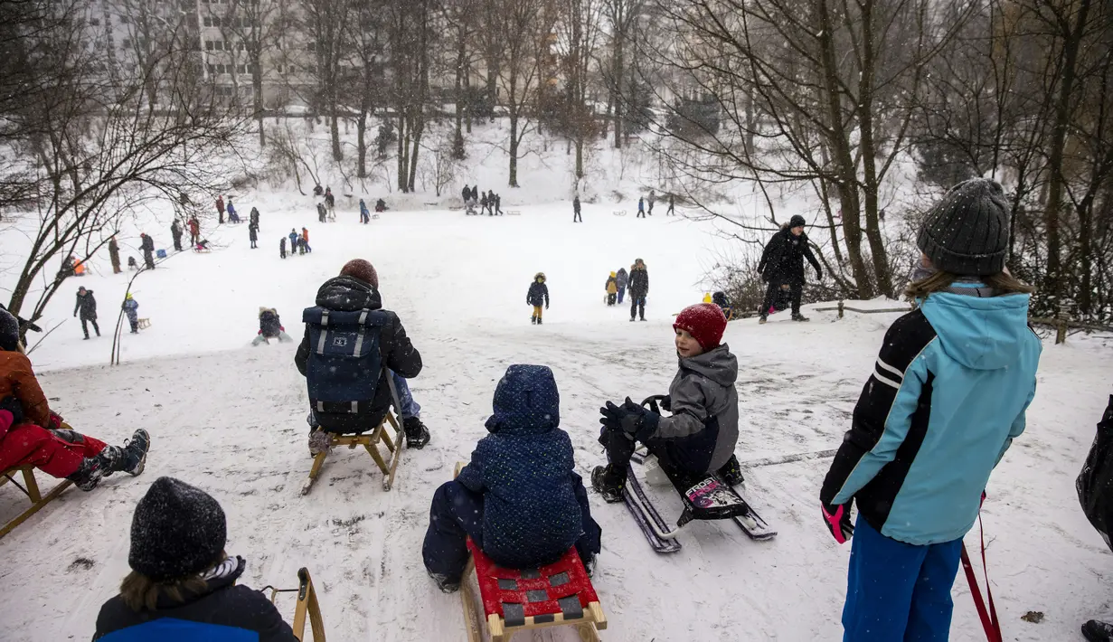 Anak-anak meluncur menuruni bukit saat mereka memanfaatkan salju tebal di taman Wilmersdorf-Schoeneberg di distrik Schoeneberg Berlin (8/2/2021). Hujan salju, hembusan angin kencang, dan suhu di bawah nol di utara dan Jerman bagian barat telah menyebabkan gangguan perjalanan. (AFP/ Odd Andersen)