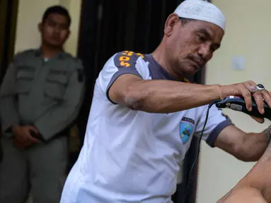 Polisi saat mencukur rambut salah satu anak Punk di Banda Aceh (9/1). Sebanyak 30 orang anak Punk ditahan oleh Polisi Syariah di Aceh. (AFP Photo/Chaideer Mahyuddin)