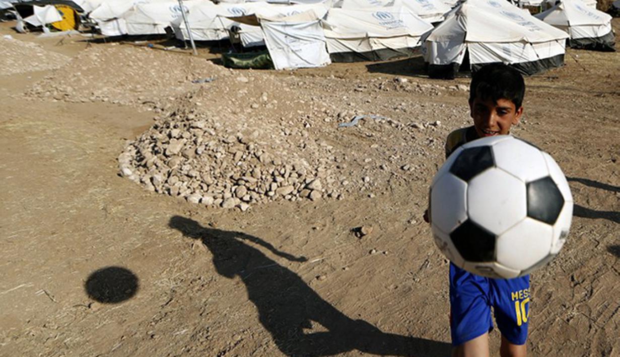 Bocah Sihite asal Irak bermain sepak bola. (AFP PHOTO/KARIM SAHIB)
