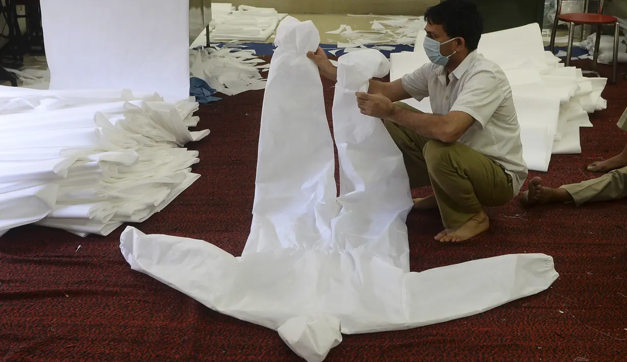Personel Pasukan Polisi Cadangan Sentral (CRPF) memperlihatkan baju Alat Pelindung Diri di sebuah workshop polisi selama penerapan lockdown di New Delhi, Minggu (12/4/2020). India mengalami krisis alat pelindung diri (APD) di tengah pandemi virus corona. (SAJJAD HUSSAIN/AFP)