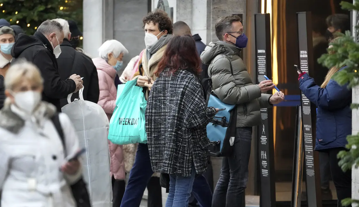 Orang-orang menunjukkan status vaksinasi mereka saat antre di depan department store terkenal 'KaDeWe' (Department Store Of The West) di Berlin, Selasa (21/12/2021). Jerman akan memperkenalkan langkah-langkah baru untuk mengekang penyebaran COVID-19 sebelum Malam Tahun Baru. (AP Photo/Michael Sohn)