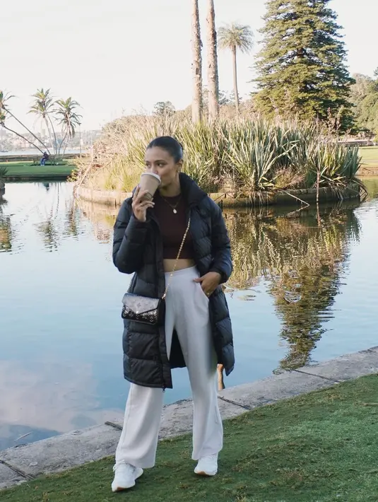 Amanda Rawles tampil cantik walau hanya berpose minum kopi. Ia tampak mengenakan cropped top hitam, dipadu dengan celana panjang putih, kemudian dilapisinya dengan puffer coat hitam. Ia juga membawa sling back dan menyempurnakannya dengan sneakers putih untuk kesan yang lebih kasual. Foto: Instagram.