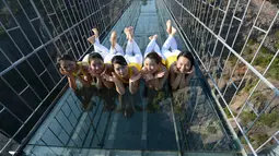 Para perempuan berpose saat melakukan yoga di jembatan kaca di Taman Nasional Shiniuzhai di Pingjiang, provinsi Hunan, China, Kamis (5/11). Latihan di atas ketinggian 180 meter ini untuk mempromosikan hidup sehat dengan beryoga. (REUTERS/China Daily)