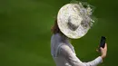 Seorang penonton balap berswafoto saat menghadiri hari pertama balap kuda Royal Ascot, di Ascot, barat London Selasa (15/6/2021). Balap kuda eksklusif yang hanya dihadiri oleh kalangan elit Inggris itu menjadi tradisi tahunan sejak tahun 1711. (DANIEL LEAL-OLIVAS / AFP)