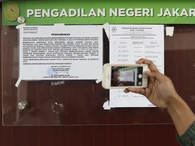 Pengunjung mengambil gambar pengumuman pembekuan Jamaah Ansharut Daulah (JAD) di salah satu papan pengumuman PN Jakarta Selatan, Senin (6/8). Jaksa melaksanakan eksekusi putusan pembekuan JAD sebagai organisasi terlarang. (Liputan6.com/Herman Zakharia)