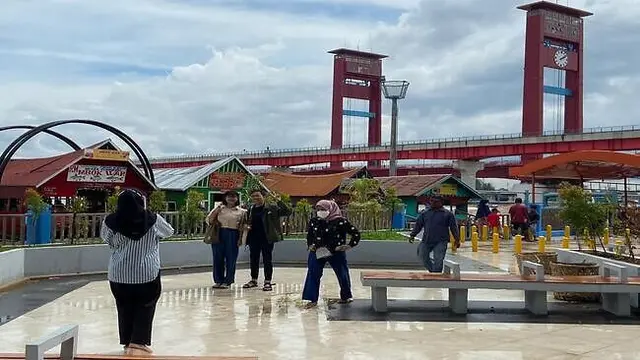 Pengunjung Plaza 16 Ilir berfoto dengan latar sungai Musi dan jembatan Ampera, Senin (23/01/2022).