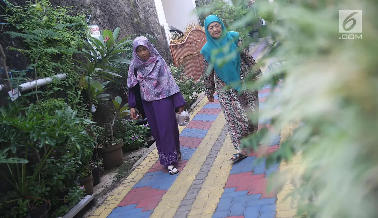 Warga melintas di salah satu gang kampung hijau di kawasan Malakasari, Jakarta, Sabtu (15/9). Tingginya kesadaran masyarakat akan pentingnya tumbuhan membuat kawasan tersebut terlihat asri dan dipenuhi berbagai tanaman. (Liputan6.com/Immanuel Antonius)