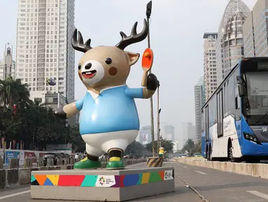 Bus Transjakarta melintas di samping patung maskot Asian Games 2018 yang menghiasi Jalan Sudirman, Jakarta, Rabu (8/8). Pemasangan maskot tersebut untuk menyemarakan Asian Games 2018 yang akan dibuka 18 Agustus 2018. (Liputan6.com/Immanuel Antonius)