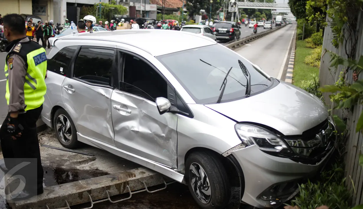 Polisi berjaga didekat mobil yang menabrak separator busway matraman arah kampung melayu, Jakarta, Sabtu (25/2). (Liputan6.com/Faizal Fanani)