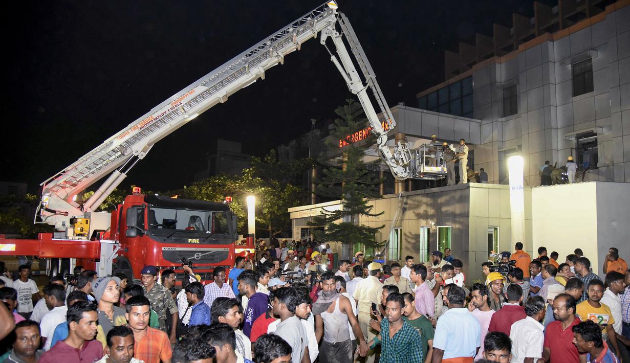 Warga berkumpul saat petugas pemadam berusaha mengevakuasi korban yang terjebak kebakaran  besar di rumah sakit SUM Bhubaneshwar di Odisha, India Timur, Senin (17/10). Sedikitnya 19 orang tewas dan sejumlah lainnya cedera dalam peristiwa tersebut. (AFP)