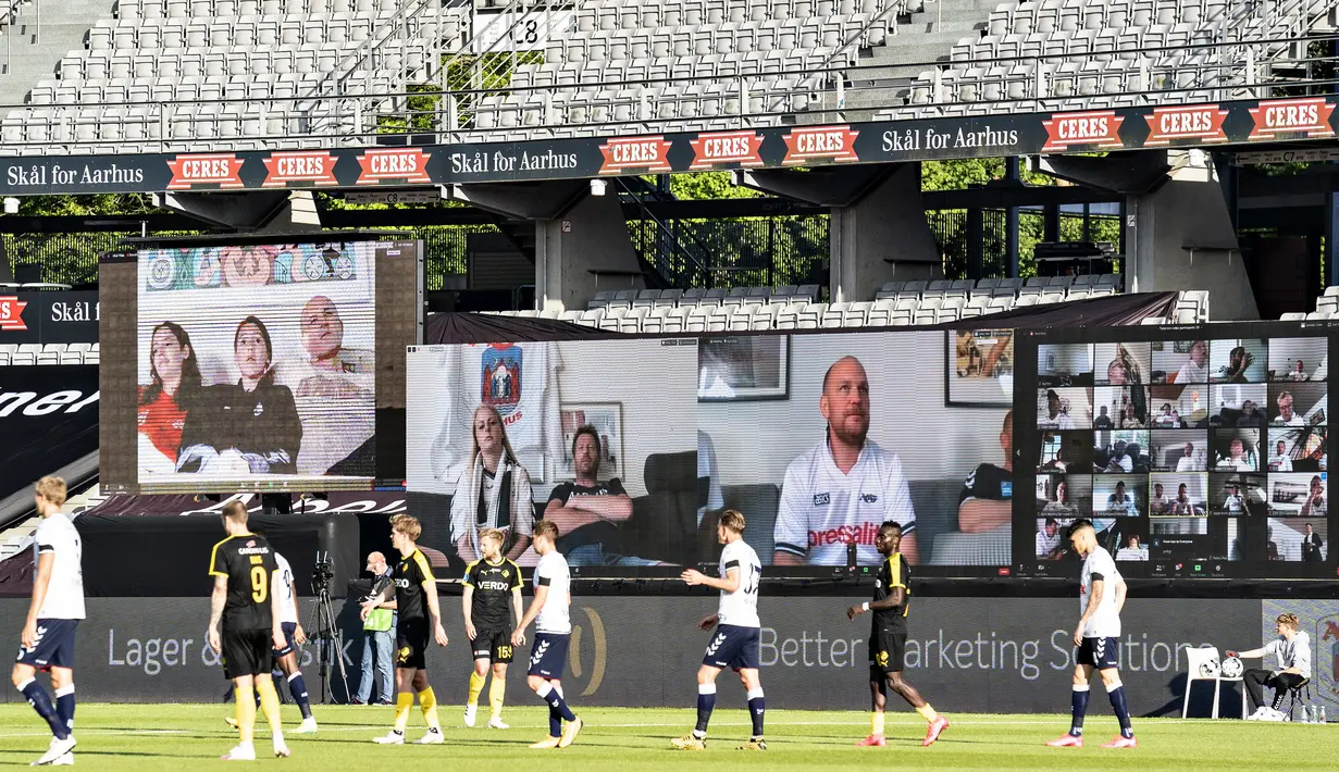 Penonton menyaksikan pertandingan Liga Denmark antara AGF dengan Randers FC melalui aplikasi video conference di Ceres Park, Aarhus, Denmark, Kamis (28/5/2020). Laga ini menjadi pertandingan pertama yang melibatkan suporter melalui aplikasi pertemuan virtual. (Henning Bagger/Ritzau Scanpix via AP)
