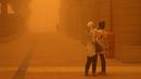 <p>Perempuan mengambil video dengan smartphone mereka di tengah badai debu parah di Kuwait City pada 23 Mei 2022. Kabut oranye tebal telah menyelimuti Kuwait pada hari Senin, menyebabkan penerbangan ke dan dari bandara internasional negara itu ditangguhkan sementara, kata regulator penerbangan sipil. (Yasser Al-Zayyat / AFP)</p>