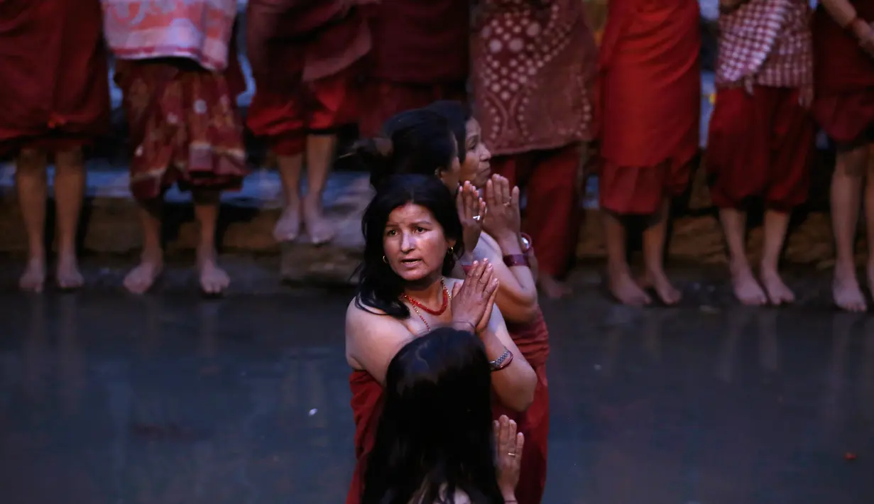 Wanita Hindu Nepal berdoa saat upacara upacara Madhav Narayan di Sungai Bagmati di Kathmandu, Nepal (27/1).  Dalam upacara ini mereka juga membaca kitab suci yang dipersembahkan untuk dewi Hindu Swasthani dan dewa Hindu Siwa. (AP Photo/Niranjan Shrestha)