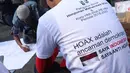 Salah satu pengurus PB HMI melihat warga yang menandatangani spanduk dukungan anti hoax di kawasan Bundaran Hotel Indonesia, Jakarta, Minggu (18/11). PB HMI mensosialisasikan Hoax sebagai ancaman demokrasi di Indonesia. (Liputan6.com/Helmi Fithriansyah)