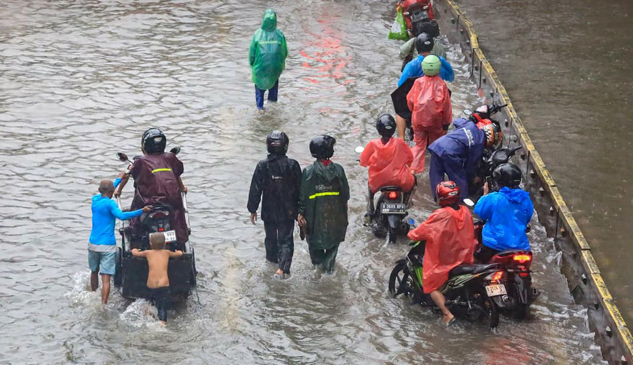 Berdasarkan laporan petugas, banjir dipicu oleh curah hujan yang tinggi dalam waktu cukup lama. Selain itu, luapan Kali Krukut turut memperparah genangan di sejumlah kawasan yang berada di sekitar aliran sungai tersebut. Tampak dalam foto, pengendara dan pejalan kaki melintasi banjir yang menggenangi Jalan Jembatan Tiga Raya, Jakarta Utara, Senin (12/1/2026). (merdeka.com/Arie Basuki)