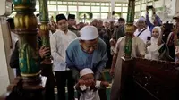 Seorang bayi baru bisa berjalan menangis saat dipapah menuju mimbar masjid dalam tradisi Batumbang Apam di Masjid Al Munnawarah, Desa Pajukungan, Kecamatan Barabai. (Liputan6.com/ Dok Pemkab HST)