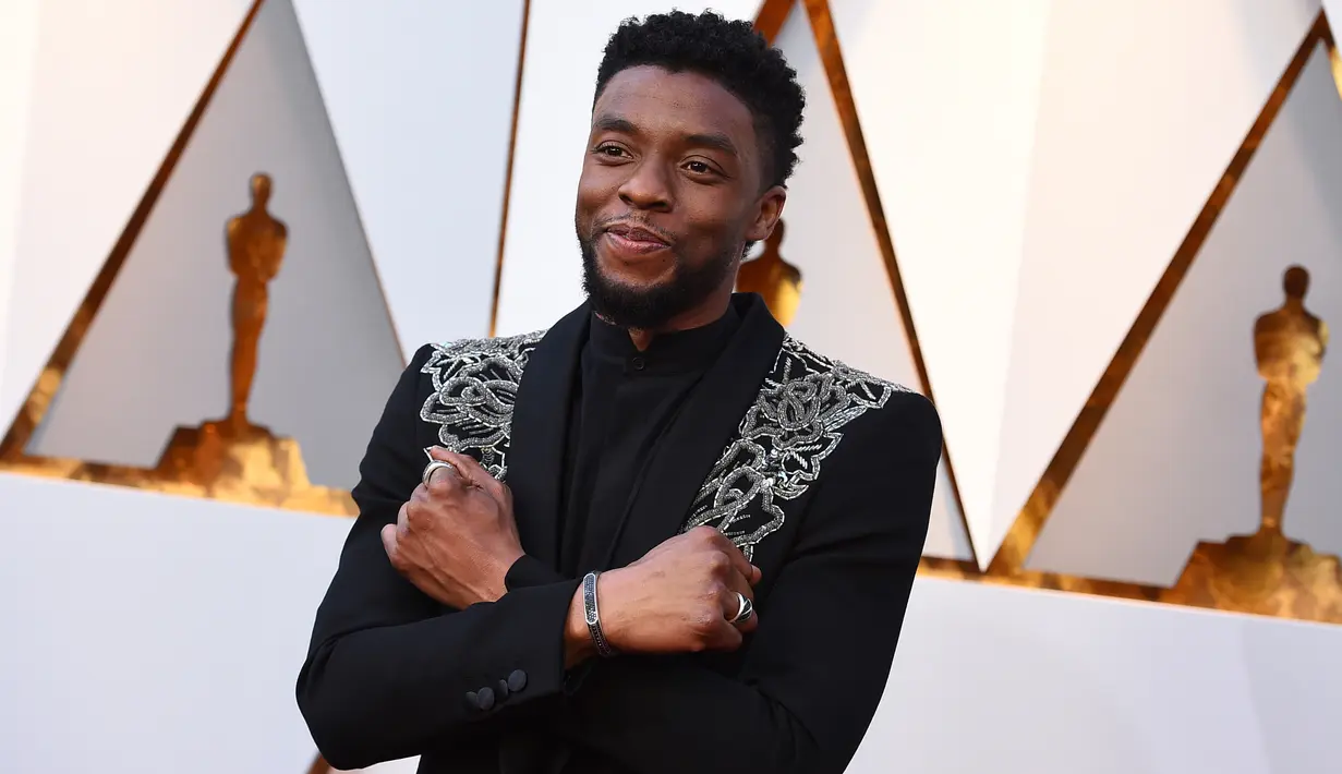 Aktor Chadwick Boseman berpose di karpet merah ajang Piala Oscar 2018, Los Angeles, Minggu (4/3). Pemeran utama Black Panther ini tampil bak raja dengan jas hitam dengan aksen perak yang melintang di bagian dada. (Jordan Strauss/Invision/AP)