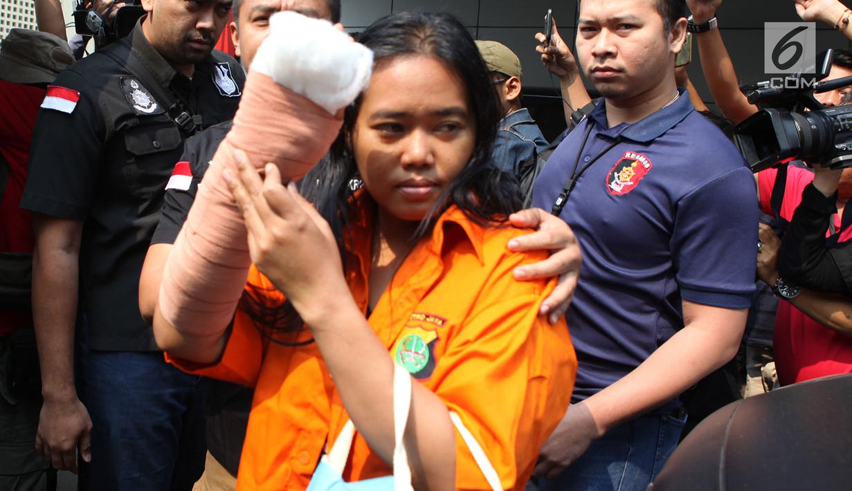 Istri tersangka pembunuhan wartawan Abdullah Fitri Setiawan alias Dufi yang tewas dalam drum, Sari menutupi wajahnya saat digelandang petugas di Polda Metro Jaya, Jakarta, Rabu (21/11). (Merdeka.com/Imam Buhori)