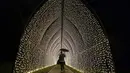 Seorang pria berjalan melalui terowongan lampu, bagian dari instalasi cahaya yang dipamerkan menyambut Natal di Royal Botanic Gardens, Kew, London, Selasa (15/11/2022). Selain memamerkan jalur cahaya dengan satu juta lampu di jalur sepanjang 2,7 km, terdapat cahaya imersif, pohon lampu, terowongan cahaya, dan pertunjukkan cahaya air yang mengesankan. (AP Photo/Kirsty Wigglesworth)