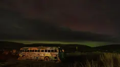 Sebuah aurora borealis, juga dikenal sebagai cahaya utara, terlihat di langit malam saat awan bergerak di atas tengara pinggir jalan yang dikenal sebagai "That NW Bus" di Washtucna, Washington, Amerika Serikat, 27 Februari 2023 dini hari. Berdenyut dalam garis-garis merah, hijau, dan ungu, aurora – juga dikenal sebagai cahaya utara – tampil semarak di belahan bumi utara dari Minggu malam hingga Senin pagi. (AP Photo/Ted S. Warren)