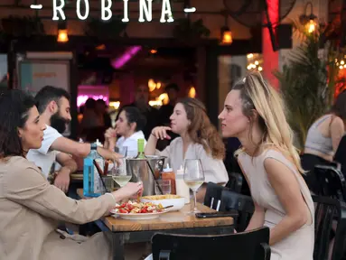 Orang-orang menikmati makanan di kafe di Abima Square di kota Tel Aviv, Israel (20/5/2021). Israel dan dua kelompok bersenjata utama Palestina di Gaza, Hamas dan Jihad Islam, menyetujui gencatan senjata untuk mengakhiri konflik selama 11 hari. (AFP/Gideon Markowicz)