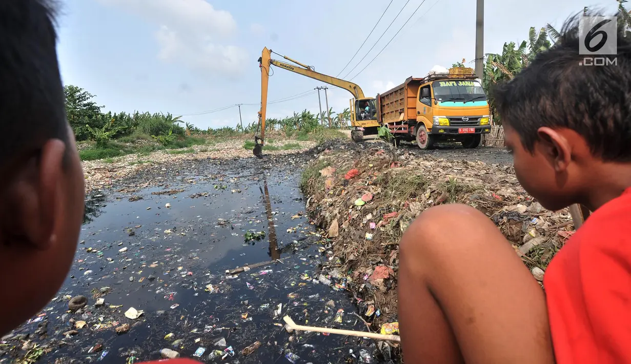Anak-anak menyaksikan pengerukan sampah Kali Pisang Batu, Tarumajaya, Bekasi, Jawa Barat, Rabu (9/1). Petugas DLH Kabupaten Bekasi mulai membersihkan sampah setelah fenomena tersebut ramai diberitakan di media sosial. (Merdeka.com/Iqbal S. Nugroho)