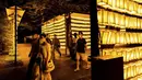 Para pengunjung berjalan melewati lentera kertas saat Festival Mitama di Kuil Yasukuni, Tokyo, Jepang, Rabu (14/7/2021). Festival Mitama dirayakan sejak 1947 untuk menghormati jiwa para arwah yang diabadikan serta tentara yang gugur dari perang Jepang di masa lalu. (BEHROUZ MEHRI/AFP)