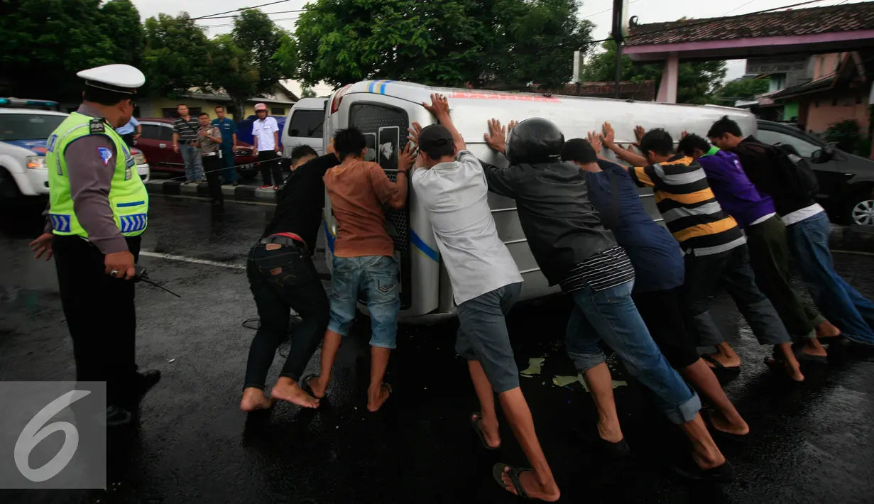 Sejumlah warga berusaha membalikkan mini bus dengan Nopol E 7054 K yang terguling di Jalan Lingkar Yogyakarta, Senin (9/5). Akibat kecelakaan tersebut jalur lingkar menuju Solo dan Kota Yogyakarta mengalami kemacetan. (Liputan6.com/Boy Harjanto)