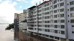 Sebuah jalan di luar gedung yang terendam banjir setelah hujan lebat di Dazhou, di provinsi Sichuan barat daya China (12/7/2021). Banjir akibat hujan lebat melanda sejumlah wilayah di China. (AFP/STR)