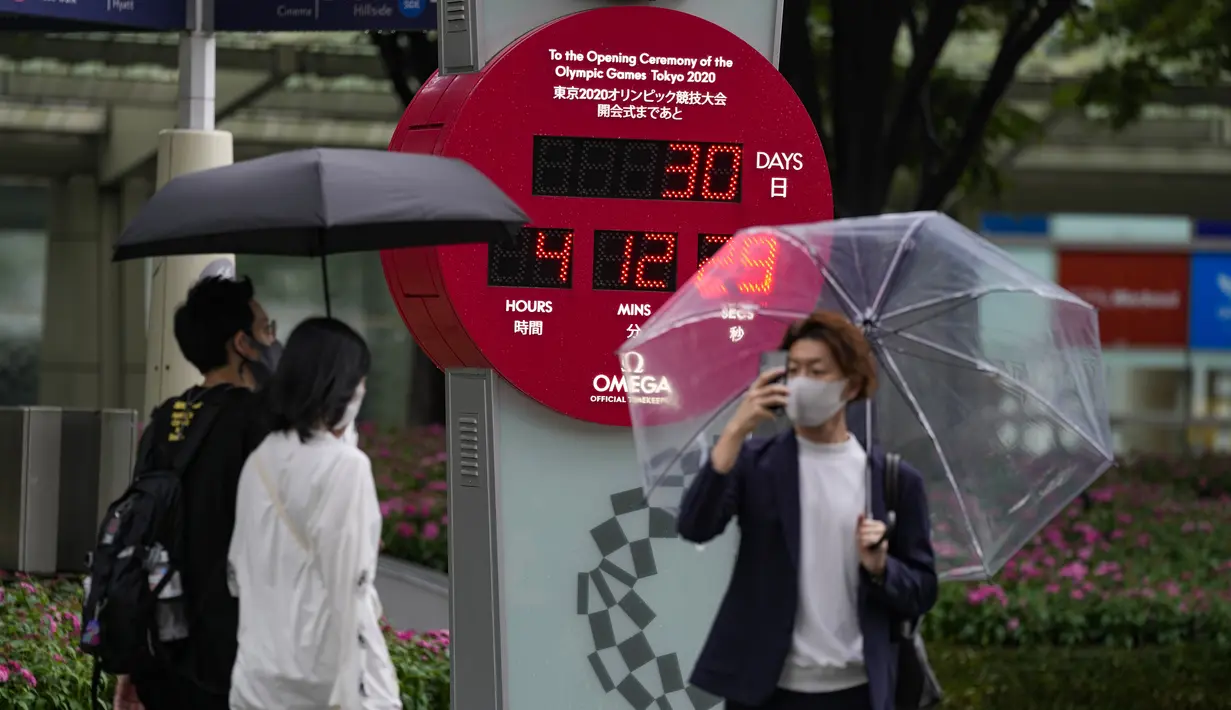 Pejalan kaki berada dekat jam hitung mundur yang menunjukkan 30 hari menuju pembukaan Olimpiade Tokyo 2020 di Tokyo, Rabu (23/6/2021). Olimpiade Tokyo dimulai pada 23 Juli dan penyelenggara mengizinkan penonton lokal menghadiri venue pertandingan dengan kapasitas 50 persen. (AP Photo/Kiichiro Sato)