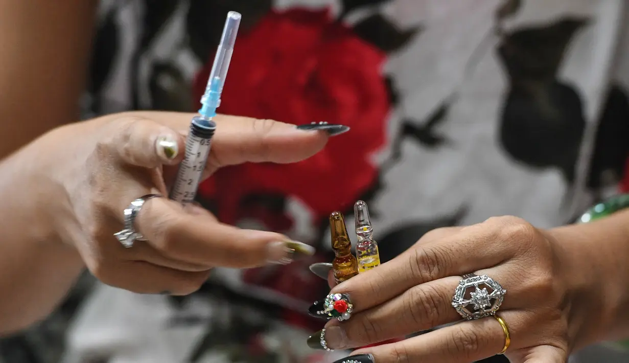  Gambar yang diambil pada 20 Februari 2017 menunjukkan Jessica Nguyen (31) mempersiapkan dosis suntik hormon di tokonya, Ho Chi Minh, Vietnam (30/3). Vietnam merupakan salah satu negara yang menolak keras transgender. (AFP Photo/Hoang Dinh Nam)