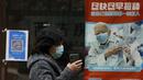 Seorang wanita mengenakan masker berjalan di dekat poster yang mempromosikan vaksinasi COVID-19 di pusat kesehatan masyarakat di Beijing, Rabu (26/10/2022). Kota Shanghai di China mulai memberikan vaksin COVID-19 yang dapat dihirup pada hari Rabu di tempat yang tampaknya menjadi yang pertama di dunia. (AP/Andy Wong)