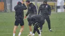 Para pemain Dortmund di sekitar Felix Nmecha (tengah) dikejutkan dengan hujan deras saat sesi latihan di Dortmund, Jerman, Senin (15/4/2024). (Bernd Thissen/dpa via AP)