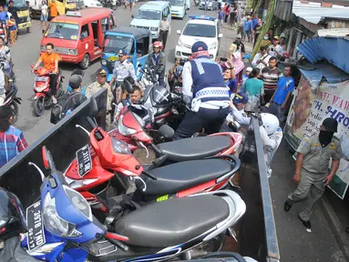 Petugas Dishub DKI mengangkut motor yang parkir di bahu jalan kawasan Kebayoran Lama, Jakarta, Kamis (12/5). Razia dilakukan untuk menertibkan kawasan itu & membuat jera pengendara yang memarkir kendaraan bukan pada tempatnya (Liputan6.com/Gempur M Surya)