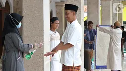 Petugas memberikan hand sanitizer sebelum Salat Jumat di Masjid El-Syifa, Jakarta, Jumat (20/3/2020). MUI dan Pemprov DKI Jakarta menginstruksikan untuk meniadakan sementara Salat Jumat selama dua pekan terkait merebaknya virus corona atau COVID-19. (Liputan6.com/Fery Pradolo)