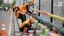 Pasukan oranye atau PPSU melakukan pengecatan jembatan layang dengan warna-warna ceria di Kampung Makasar, Jakarta, Kamis (26/7).  Pengecatan dilakukan guna mempercantik dan menyambut Asian Games 2018 pada Agustus mendatang.  (Liputan6.com/Faizal Fanani)