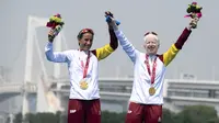 Peraih medali emas Susana Rodriguez dari Spanyol dan pemandunya Sara Loehr berpose dengan medali mereka setelah berkompetisi dalam kategori triathlon putri PTVI selama Paralympic Games Tokyo 2020 di Odaiba Marine Park di Tokyo pada 28 Agustus 2021. (CHARLY TRIBALLEAU / AFP)