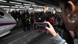 Seorang wanita mengabadikan gambar saat para pengunjuk rasa memblokir rel kereta api di Stasiun Sants di Barcelona (8/11). Pengunjuk rasa memblokir jalan dan jalur kereta api setelah para pemimpin separatis ditahan di Madrid. (AFP Photo/Lluis Gene)