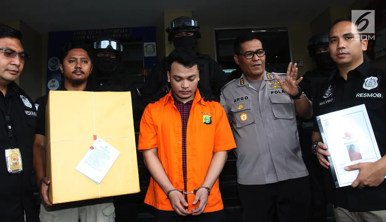 Kabid Humas Polda Metro Jaya Kombes Pol Argo Yuwono (dua kanan) bersama tersangka pembunuh satu keluarga di Bekasi Haris Simamora (tengah) saat akan pelimpahan berkas ke Kejari Bekasi di Polda Metro Jaya, Jakarta, Kamis (21/2). (Merdeka.com/Imam Buhori)