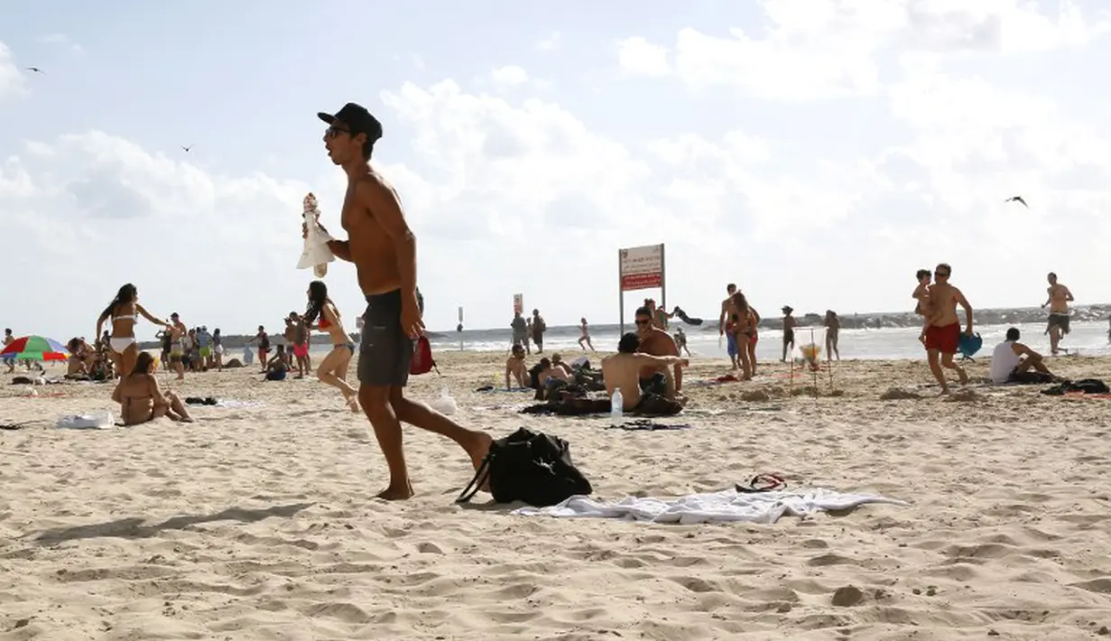 Mengetahui pantai akan menjadi sasaran balasan dari militan Palestina, warga Israel yang sedang rekreasi di pantaipun segera menyelamatkan dirinya, Israel, Senin (14/07/2014) (AFP PHOTO/GALI TIBBON)