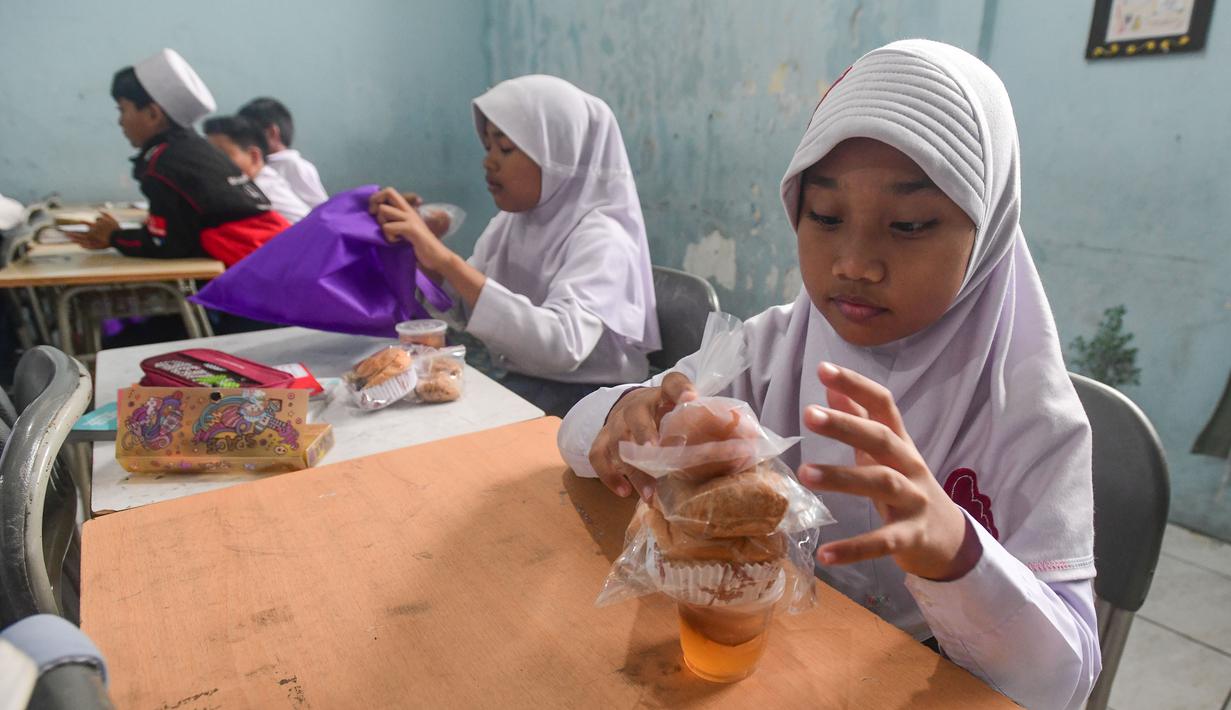 Makan Bergizi Gratis (MBG) tetap dibagikan di sekolah pada jam belajar namun dalam bentuk paket makanan kering agar bisa dibawa pulang dan dikonsumsi saat waktu berbuka. Tampak dalam foto, siswa menerima makanan program Makan Bergizi Gratis (MBG) Ramadan di SDI Al Hidayah, Cinere, Depok, Selasa (24/2/2026). (merdeka.com/Arie Basuki)