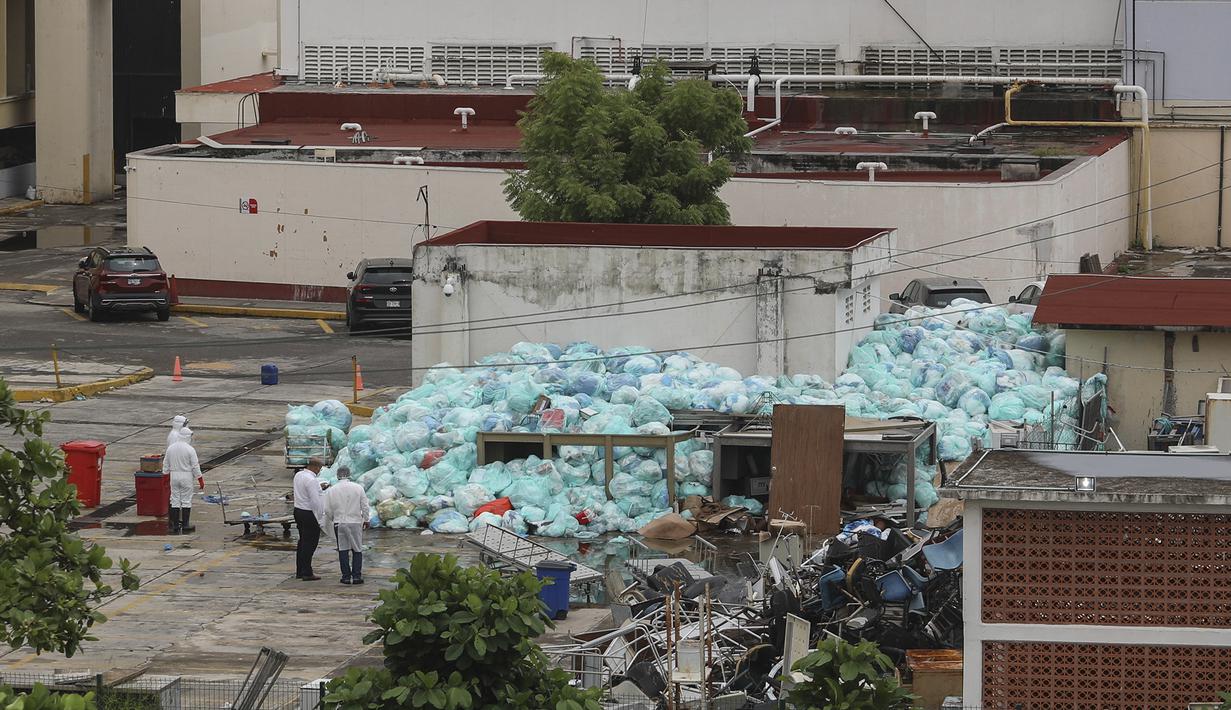 Petugas medis mengenakan alat pelindung diri saat membuang limbah biologis berbahaya di luar Rumah Sakit del Instituto Mexicano del Seguro Social, Veracruz, Meksiko, Rabu (12/8/2020). Pembuangan limbah medis yang tidak tepat menjadi masalah di tengah pandemi COVID-19. (AP Photo/Felix Marquez)