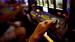 Seorang wanita lansia menekan tombol saat bermain mesin slot di Dover Downs Casino, Delaware (5/6). Legalisasi ini dilakukan sejak keputusan Mahkamah Agung yang mencabut larangan federal setelah 25 tahun lalu. (Mark Makela/Getty Images North America/AFP)