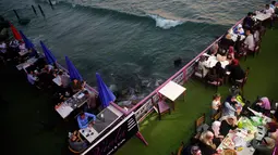 Keluarga Palestina menikmati makanan di sebuah restoran di sepanjang pantai di Kota Gaza (10/6/2019). Pergi ke restoran di dekat pantai merupakan opsi bagi warga Palestina untuk menikmati suasana alam. (AFP Photo/Mohammed Abed)