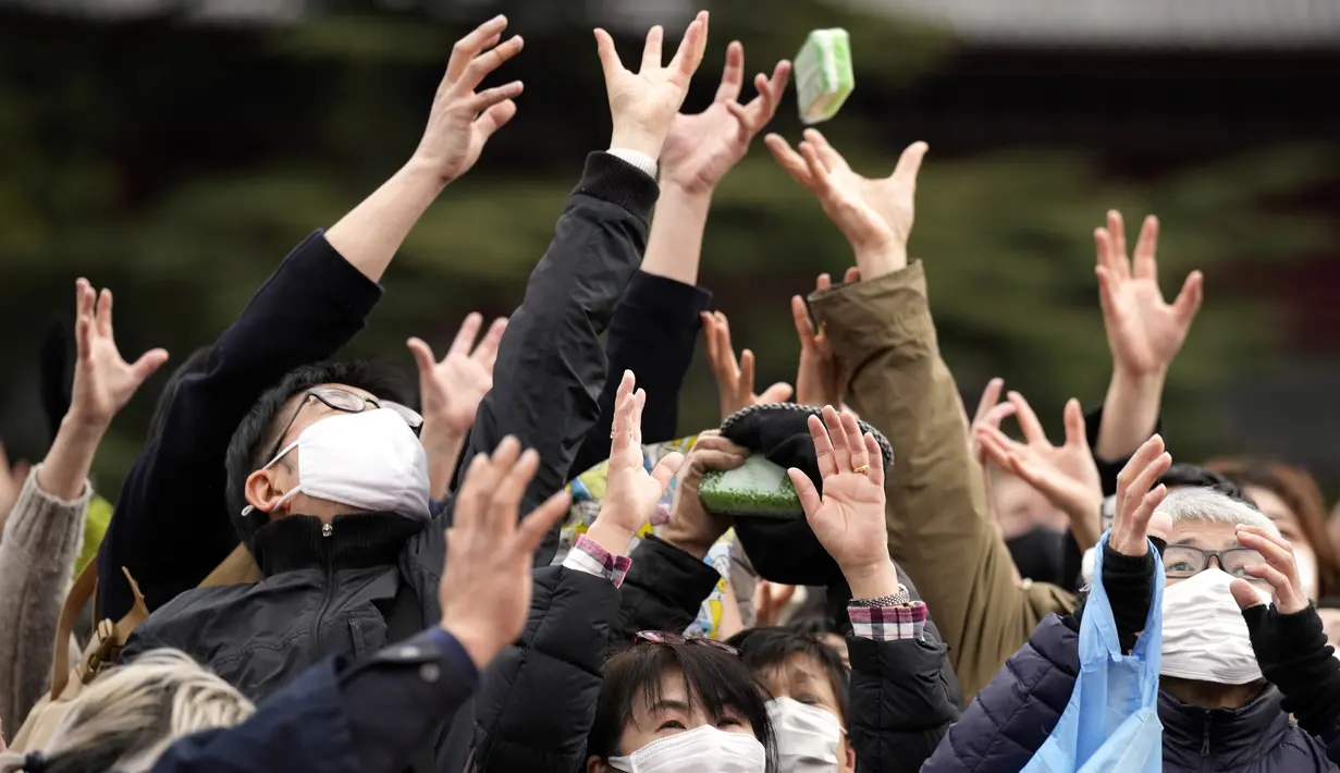 Orang-orang mencoba menangkap kacang keberuntungan yang disebarkan selama "Mame-maki", upacara melempar kacang, di kuil Buddha Zojoji, Tokyo, Jumat (3/2/2023). Ritual yang diyakini membawa keberuntungan dan mengusir kejahatan ini dilakukan setiap tahun untuk menandai awal musim semi dalam kalender lunar. (AP Photo/Eugene Hoshiko)