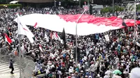 Peserta aksi massa Gerakan Nasional Kedaulatan Rakyat mengibarkan bendera Merah Putih raksasa saat melakukan unjuk rasa di perempatan dekat Gedung Bawaslu, Jakarta, Rabu (22/5/2019). Dalam aksinya, mereka meminta Bawaslu memeriksa kembali hasil Pemilu 2019. (Liputan6.com/Helmi Fithriansyah)