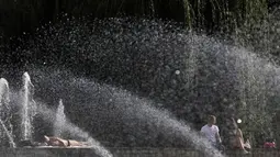 Sejumlah orang beristirahat di dekat air mancur di Taman Battersea, London, Inggris, Selasa (13/9). Taman Battersea menjadi tempat favorit warga saat cuaca panas melanda Inggris. (REUTERS / Stefan Wermuth)